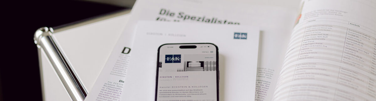 Foto mit einem Handy, das auf einer geöffneten Zeitschrift liegt. Man sieht auf dem Handy die Webseite von Eckstein & Kollegen.